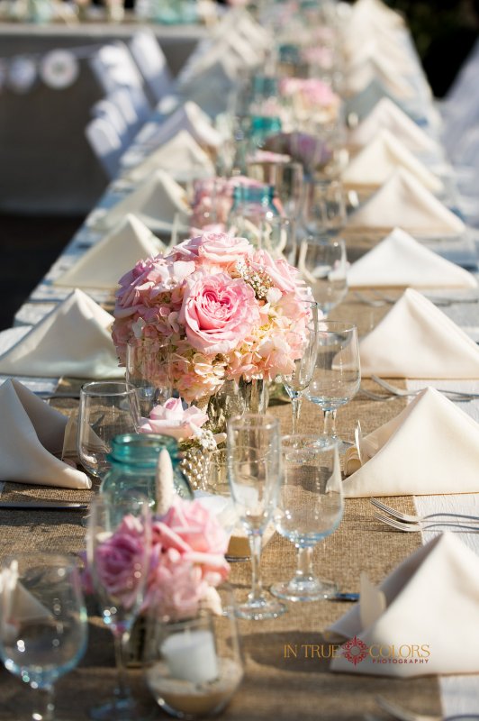 Feasting table with burplap runner and pink flowers in mercury vases
