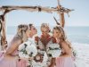 Bride and Bridesmaids under Wedding Arch on Beach