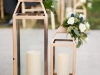 Set of Large Gold Lanterns at Back of Aisle with Candle and Flowers on Top